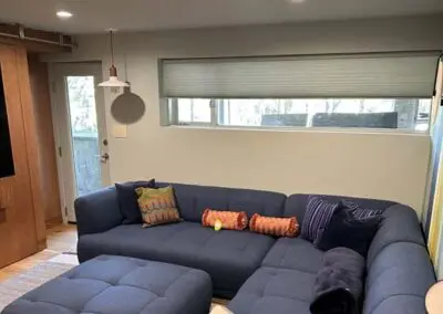Modern living room with blue sectional sofa, decorative pillows, natural light.