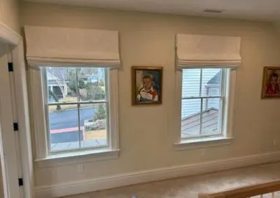Two windows with Roman shades in cozy hallway interior.