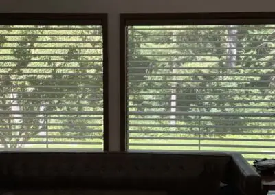 Modern window blinds filtering sunlight in cozy living room setting.
