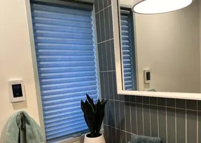 Modern bathroom with blue roller shades and smart thermostat.